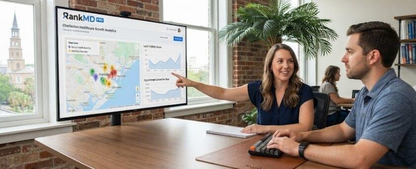 A marketing strategist pointing to a digital display showing a local healthcare growth analytics dashboard for Charleston practices, with office team members collaborating in a room overlooking historic brick architecture.